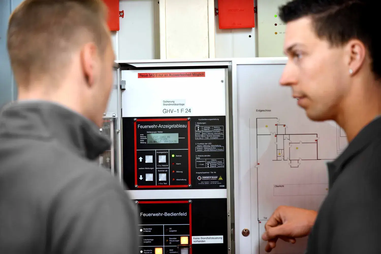 Two CWS service technicians look at a hazard detection system