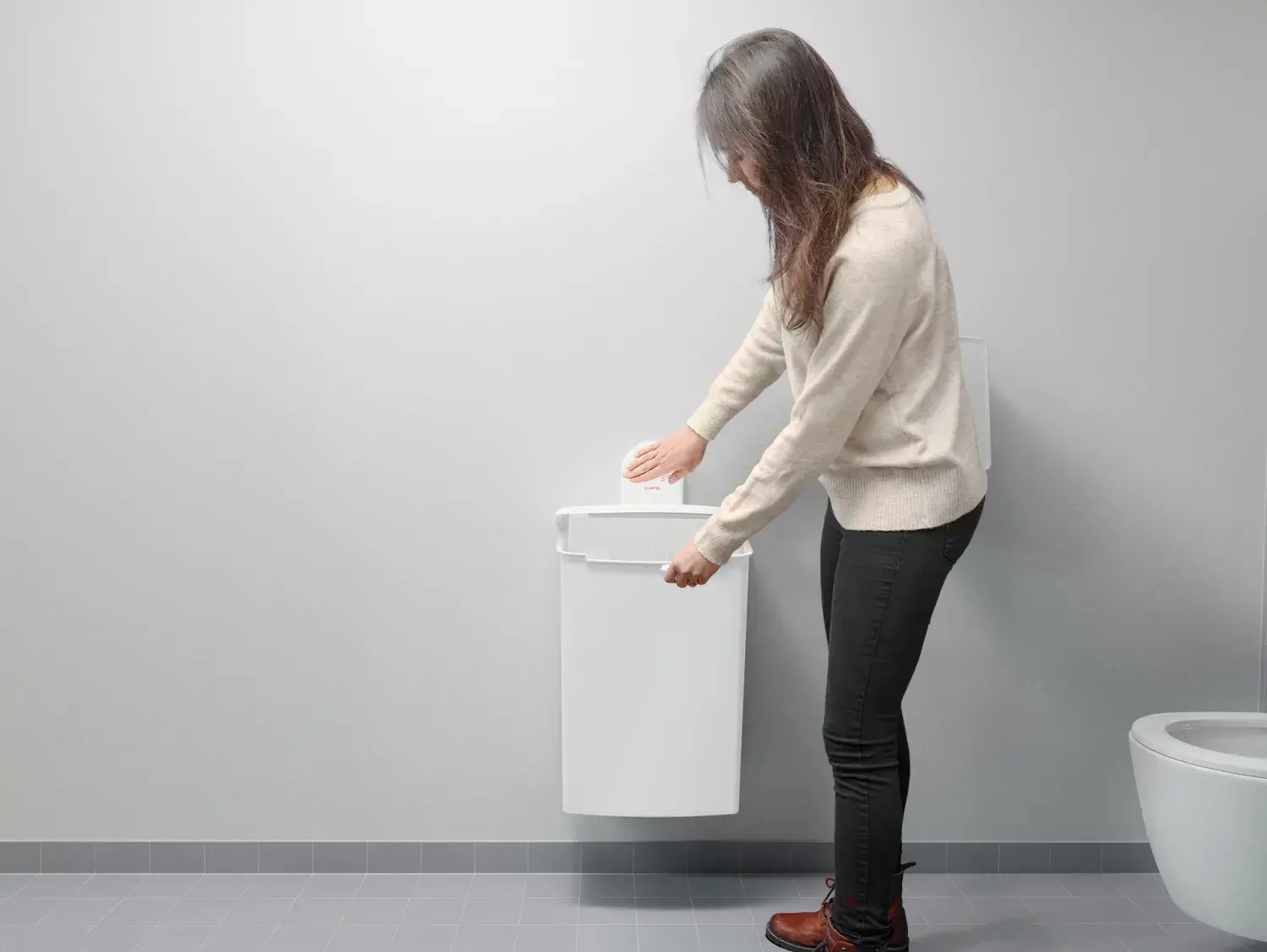 Woman throwing away sanitary waste in a hygiene box from CWS