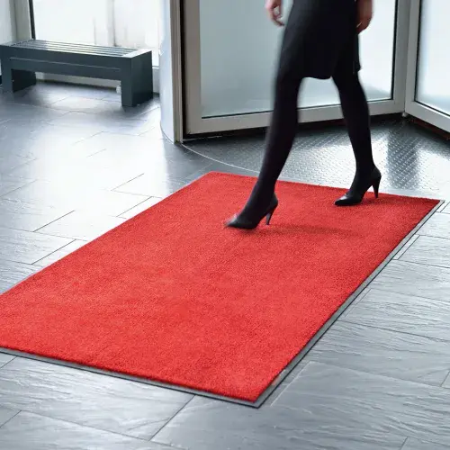 Eine Frau betritt eine rote Standardmatte im Eingangsbereich