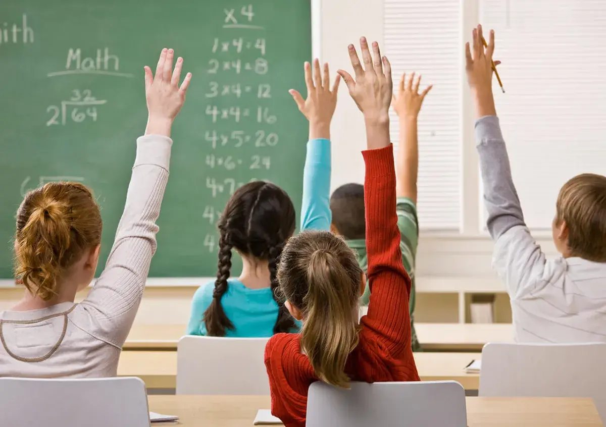 Kinderen steken hun hand op tijdens de les op school