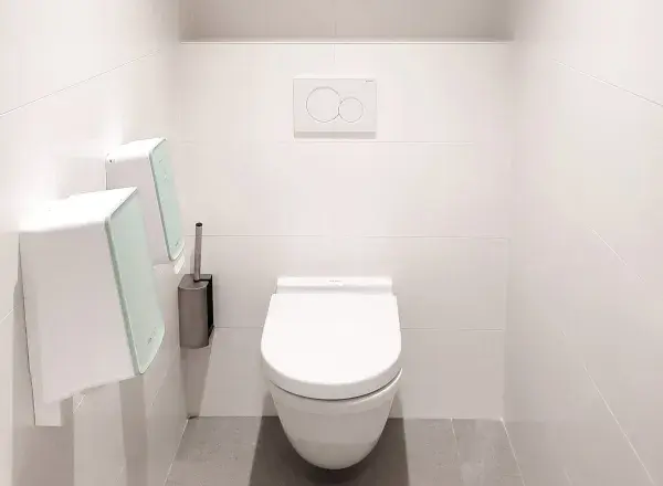 A toilet cublicle with white tiles equipped with PureLine products from CWS